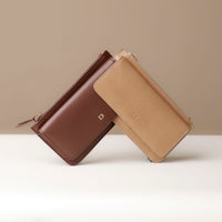 Two leather wallets, one brown and one beige, on a neutral background.