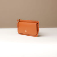 Brown leather handbag on a white surface with a beige background