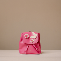 A small bright pink leather backpack with a flap closure, decorated with two white flower appliqués and a white butterfly applique on the front, set against a neutral beige background.