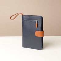 Globetrotters Document Holder navy blue with tan, with silver hardware, with a tan brown strap, lateral view
