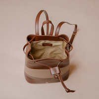 A brown leather mini bucket bag with a beige horizontal stripe and a beige quilted interior lining, shown from a top-down view on a solid beige background.