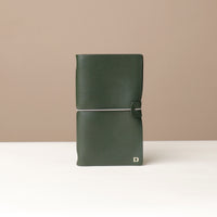 A Green leather journal with a silver elastic band on a leather surface.