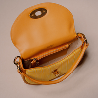 A bag in warm tan leather and textured gold fabric, shown open to display its interior zippered pocket and gold-tone hardware against a neutral beige background.