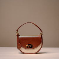 A brown leather handbag with a curved top handle, a cream-colored woven lower section, and gold-tone hardware, photographed against a neutral beige background.