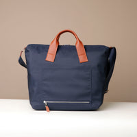Navy blue bag with brown leather handles on a beige background