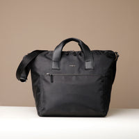 Black bag with a shoulder strap on a beige background