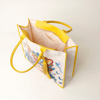 Top view of open yellow Mercatto Tote Bag with double leather handles and woven detail