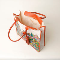 Top view of open orange Mercatto Tote Bag with double leather handles and woven detail