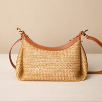 Mini Mia 26 Raffia tan handcrafted with raffia and premium leather, with gold hardware and a leather strap, in a beige background, back view
