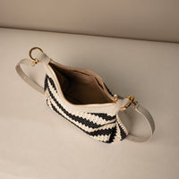 Open view of a Mini Mia 26 Raffia Arena handcrafted with raffia and premium leather, with gold hardware and a leather strap, in a beige background

