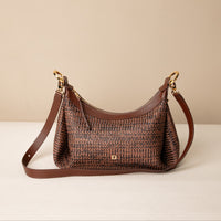 Mini Mia 26 Raffia Palisander brown handcrafted with raffia and premium leather, with gold hardware and a leather strap, in a beige background, front view
