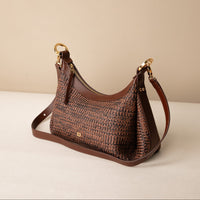 Mini Mia 26 Raffia Palisander brown handcrafted with raffia and premium leather, with gold hardware and a leather strap, in a beige background, lateral view
