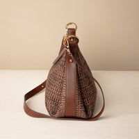Mini Mia 26 Raffia Palisander brown handcrafted with raffia and premium leather, with gold hardware and a leather strap, in a beige background, lateral view
