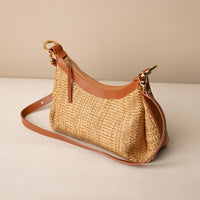 Mini Mia 26 Raffia tan handcrafted with raffia and premium leather, with gold hardware and a leather strap, in a beige background, lateral view
