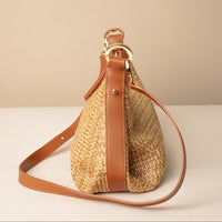 Mini Mia 26 Raffia tan handcrafted with raffia and premium leather, with gold hardware and a leather strap, in a beige background, lateral view
