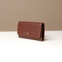 Brown leather wallet on a white surface with a beige background