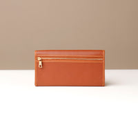 Brown leather wallet with gold zipper on a neutral background
