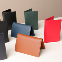 A collection of folded card wallets in various colors including black, green, blue, red, brown, and tan.