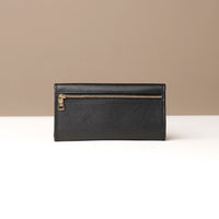 Black leather wallet with gold zipper on a neutral background