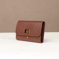 Brown leather clutch bag with a gold clasp on a beige background