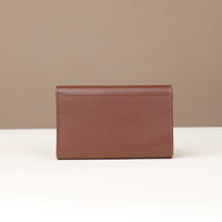 Brown leather wallet on a white surface with a beige background