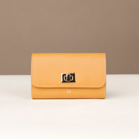 Yellow wallet with a gold clasp on a white surface with a beige background