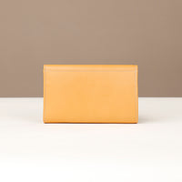 Yellow wallet on a white surface with a beige background