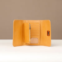 Yellow leather wallet with pen holder on a white surface and beige background