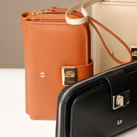 Brown leather wallet and black handbag with gold hardware on a neutral background