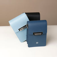 Three leather crossbody bags in black, blue, and light blue colors, displayed upright with a neutral background.