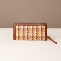 Woven wallet with brown leather trim on a beige background