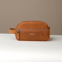 A suede tan toiletry bag 2014 with a silver zipper closure and a handle, with visible brand Danilos, placed against a neutral background. Front view. 