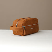 A suede tan toiletry bag 2014 with a silver zipper closure and a handle, with visible brand Danilos, placed against a neutral background. Lateral view. 