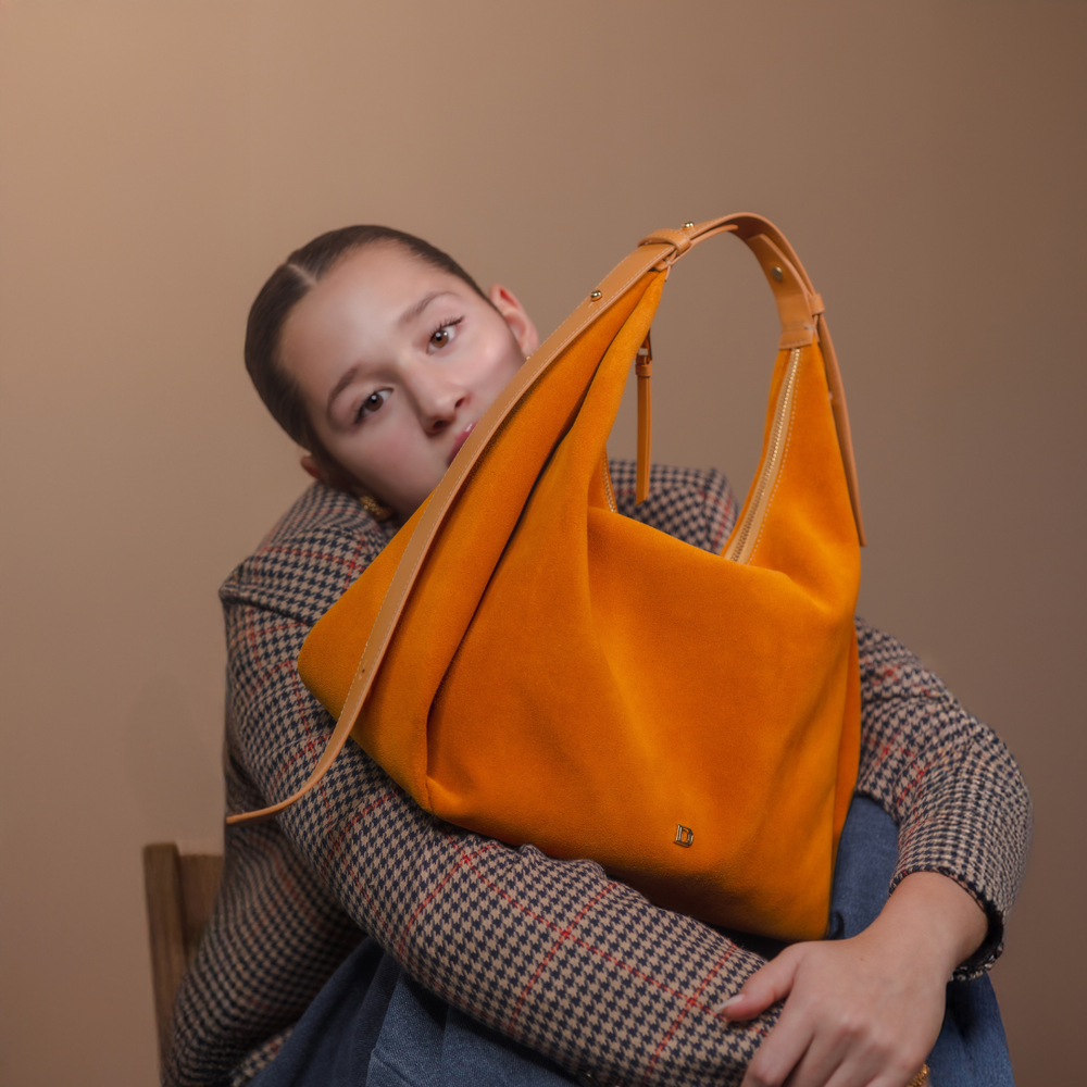 A female model with Suede Mia Minimale in tan – minimalist suede hobo bag with adjustable leather strap and slouchy silhouette