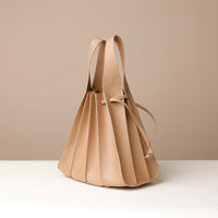 Side view of beige Papillon Bag pleated leather bucket bag by Danilo’s