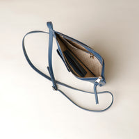 Blue handbag with a strap on a light beige background
