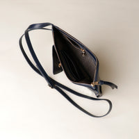 Navy blue handbag with a strap on a light beige background