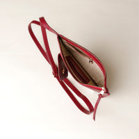 Red handbag with a gold zipper on a light beige background