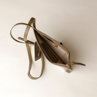 Open beige handbag with a strap on a light background