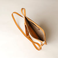 Open tan leather handbag on a light beige background