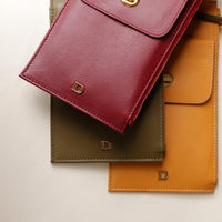 Three leather wallets in red, green, and brown with a visible brand logo on a light background