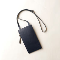 Black leather crossbody bag on a light beige background