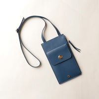 Blue crossbody bag with a strap on a light beige background