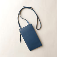Blue leather crossbody bag on a light beige background
