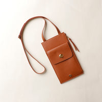 Brown leather crossbody bag on a light beige background