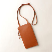 Brown leather crossbody bag on a light beige background
