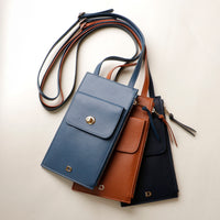 Three leather bags in blue, brown, and black on a light beige background
