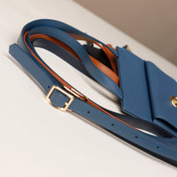 Blue handbag with gold buckle on a light gray background