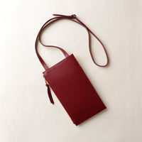 Maroon leather crossbody bag on a light beige background