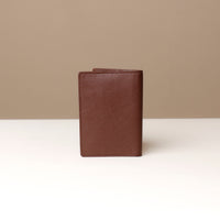 back view of a brown pebble leather passport lovable Danilos on a light surface with a neutral background